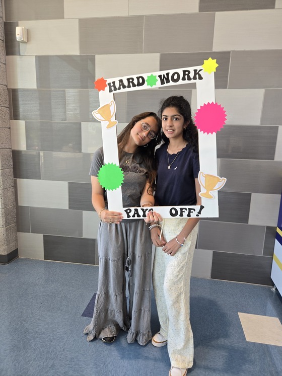 Students posing with a sign that says "Hard Work Pays Off"