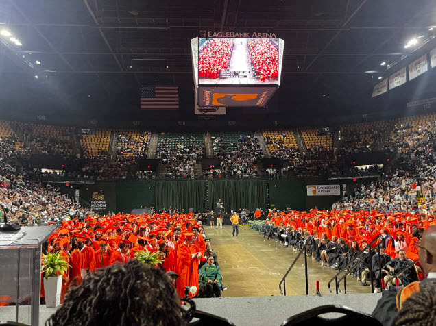 view of graduates in seats in orange robes