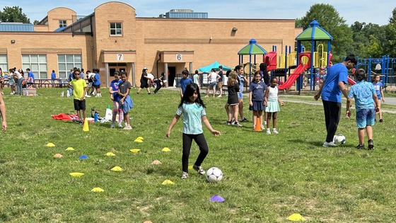 Student kicking a soccer ball through an obstacle course