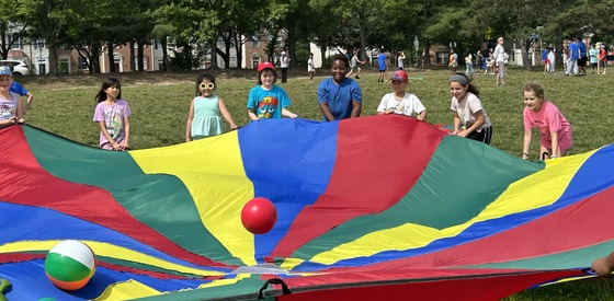 Students using a parachute to bounce beachballs