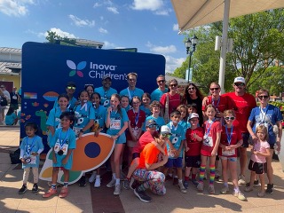 Runners posing with medals in front of Inova Children's sign