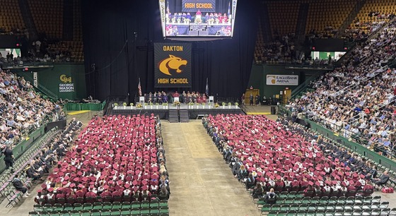 image of the class of 2026 in burgundy caps and gowns. the image is taken from behind the graduates