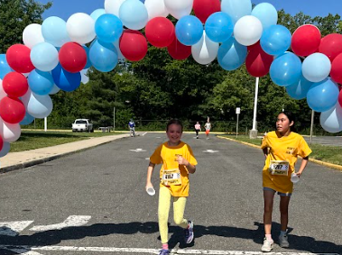 students in run club under red white and blue balloon arch