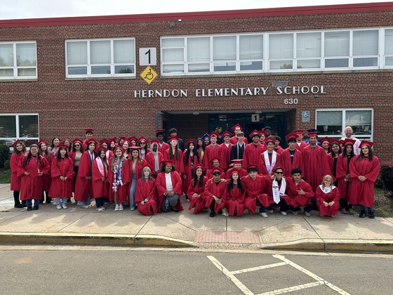 High school graduates in red caps and gowns. They are alumni of Herndon ES.