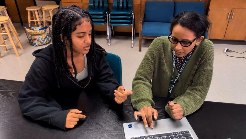 a photo of Ms. Zigita and a student working on an assignment together