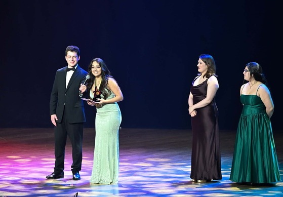 People in black tie attire on stage acceptin award