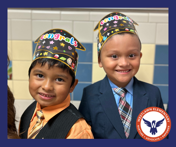 Two young boys wearing suits and paper graduation caps that say âcongratsâ in rainbow letters.