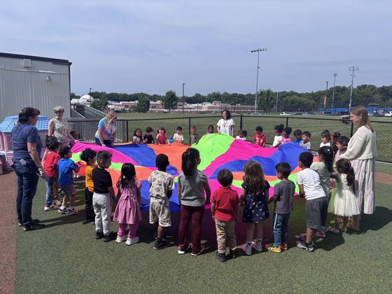 Preschool students playing with a parachute