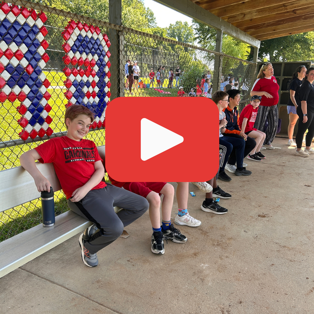 6th grade students sitting in a dugout with a red play button overlayed on the image