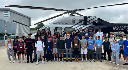Teens and adults standing together in front of Fairfax County Police Department helicopter