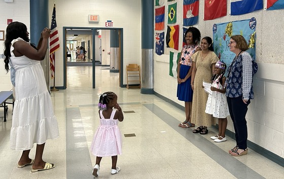 Family taking picture of their child with teachers at preschool promotion ceremony