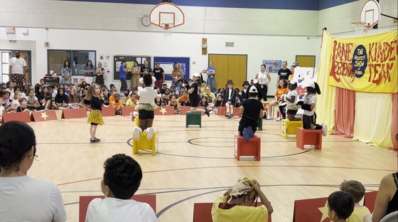 Students dressed as dogs and a dog trainer performing in the Kindergarten Circus