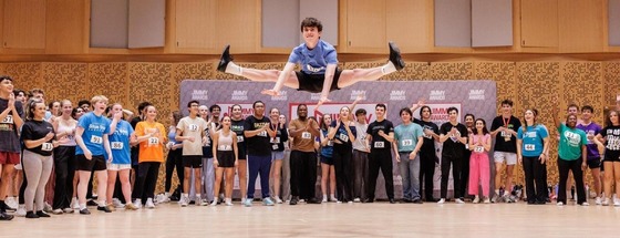 student performing on stage with other students watching in the background