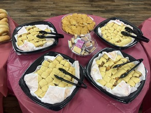 Trays of chicken minis, biscuits, and dipping sauces are arranged on a table for guests at a school event.