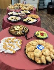 Tables filled with breakfast foods and refreshments are prepared for guests at a school event.