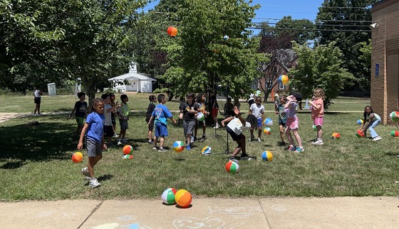 Students playing volleyball with beachballs at the 2nd grade party