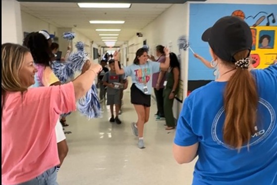 Staff members and students dancing to music in the hallway on the way to the buses