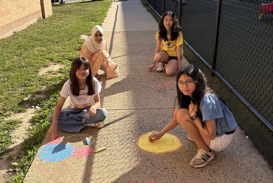 Student Ambassadors drawing designs and messages on the sidewalks near the bus loop and the Kiss and Ride door