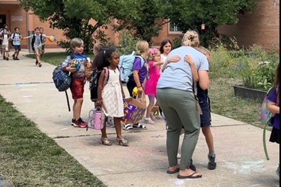 Teacher hugging students as they walk to the buses