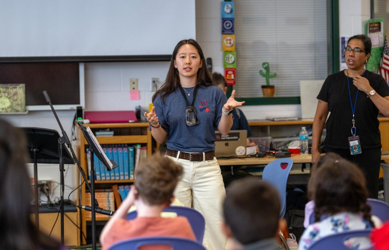 Maia Kim speaking to students from the front of a classroom