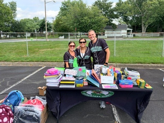 Three members of the Greenbriar East administration and PTA stand behind a table filled with donated school supplies and backpacks.