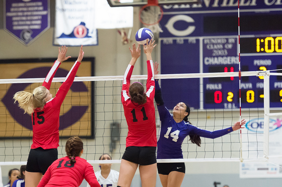 three girls spiking a volleyball during a volleyball game