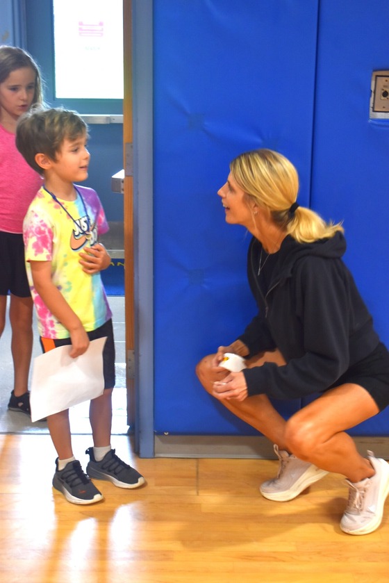 A picture of Mrs. Udasco giving a student a sticker during the kindergarten scavenger hunt