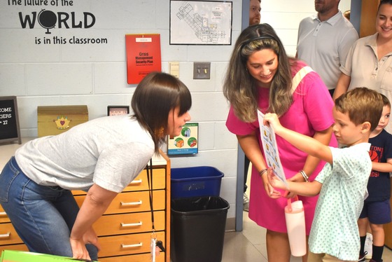 A picture of Ms. Flynn greeting one of her new students and their grownup during Open House