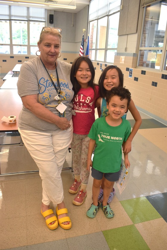 A picture of Ms. Roberts posing with 3 students during Open House