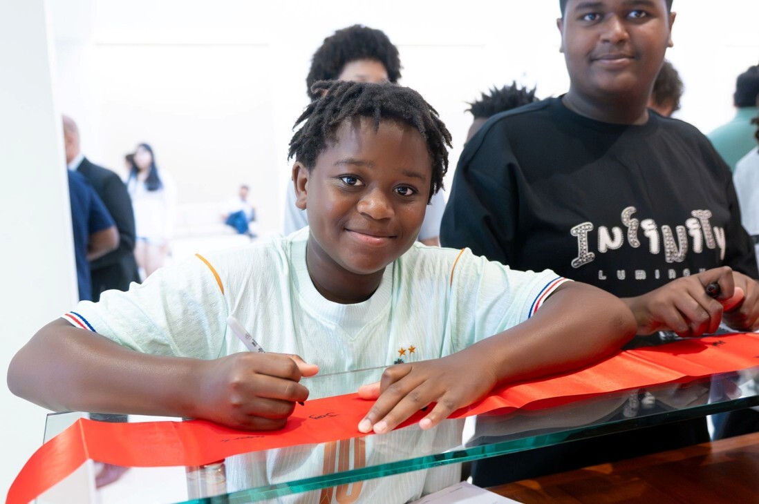 Happy student signing a red ribbon at Skyview High School for ribbon cutting ceremony.