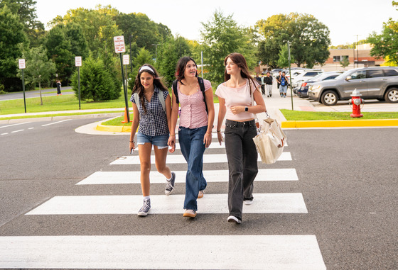 Three teen girls walk across a crosswalk.