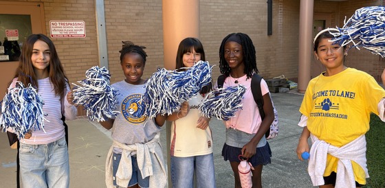 Students with pom poms welcoming students outside near the bus loop