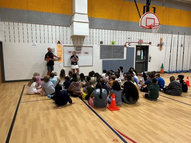 Students sitting on the gym floor listening to directions