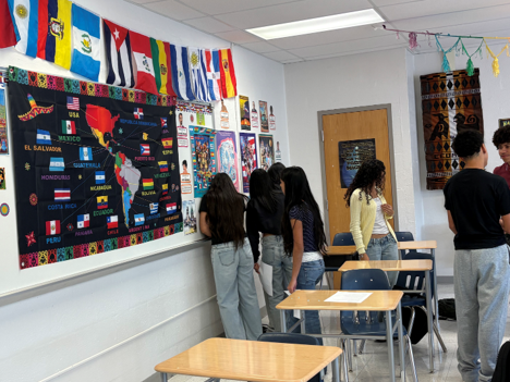 Student in class looking at bulletin board with flags in other countries.