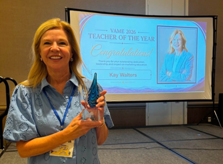 Woman standing, holding award with screen projection of her