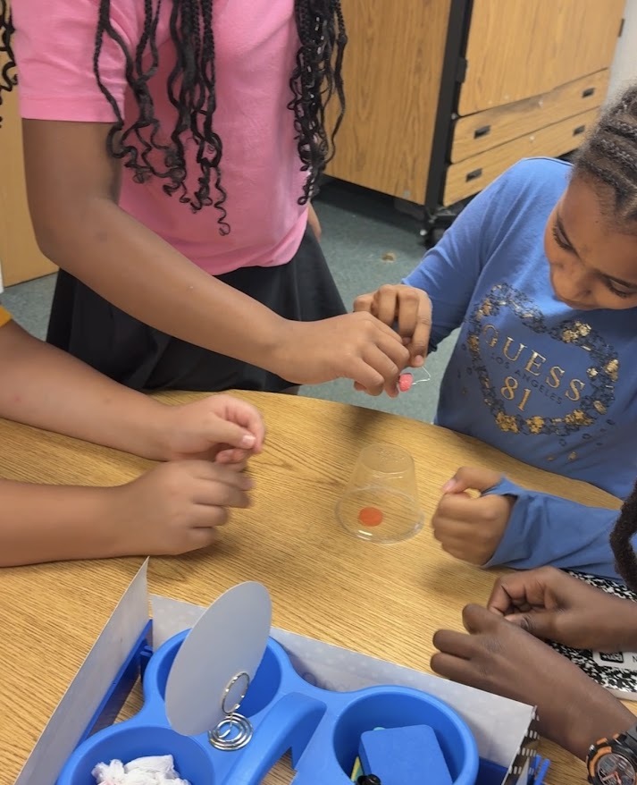 students work together to get a gummy worm into a lifesaver using paperclips