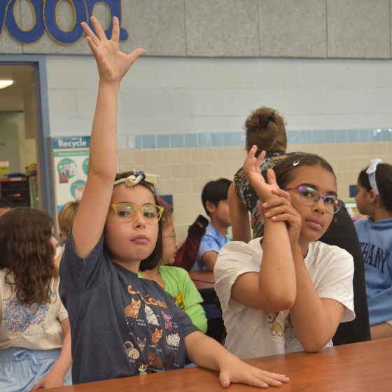 A student raising their hand in the cafeteria