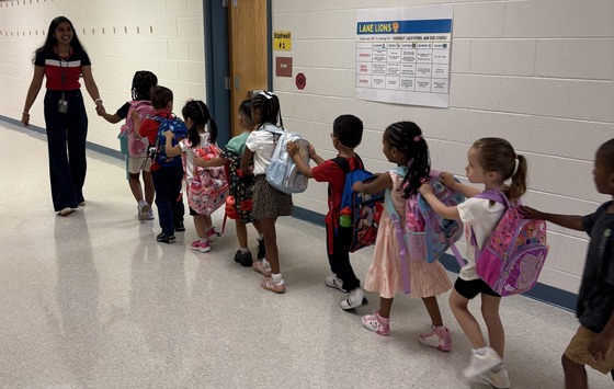 Preschoolers walking in a line holding onto each others' shoulders