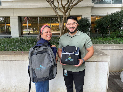 Employees showing off their employee milestone gifts of a backpack and a lunchbox