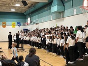 students standing on risers wearing white shirts and black pants