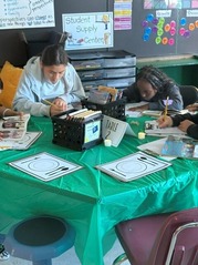 students sitting at table with green table cloth, reading books