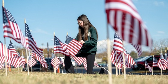 student kneeling among American flags