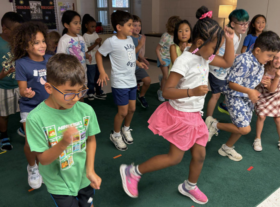 Second-grade students move their bodies to the beat during music class.