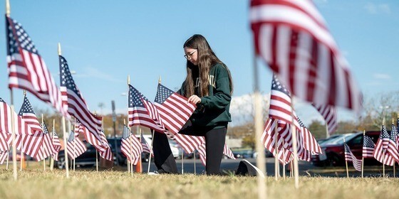 a student stands among a field of American Flags