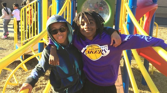 Two boys on the playground with their arms around each others' shoulders