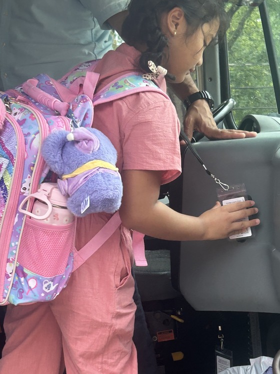 A student taps onto the bus with her bus pass.