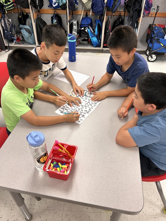 Four boys sitting at a table working on a Math activity