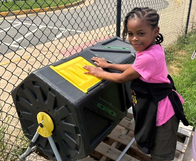 A student turning the composter on the playground