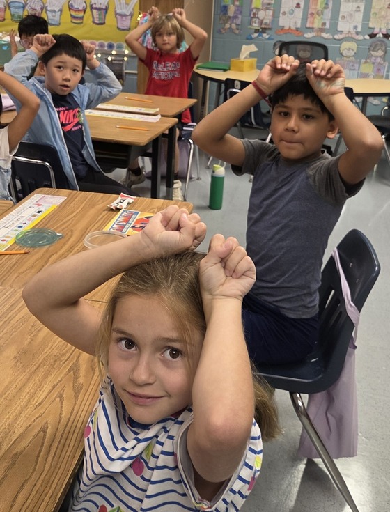 Students putting their panda paws up to show they are watching and listening as well as their panda spirit.
