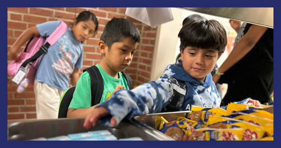 A student reaches for a juice at the breakfast cart in the hallway.